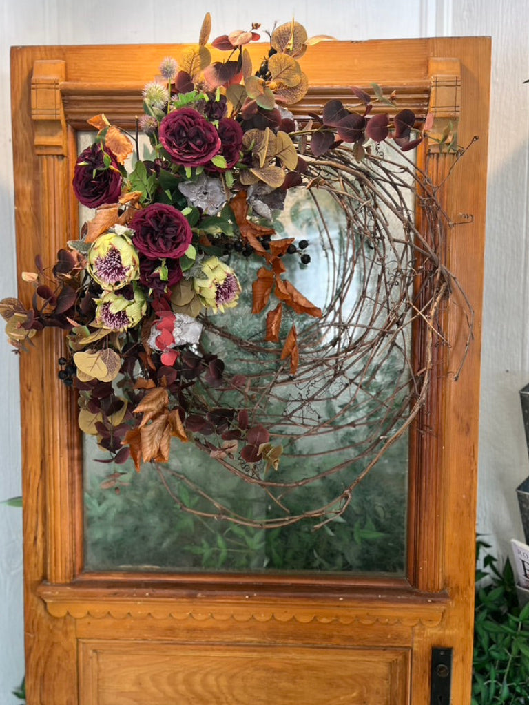 Decorative wreath with flowers and leaves on a wooden door