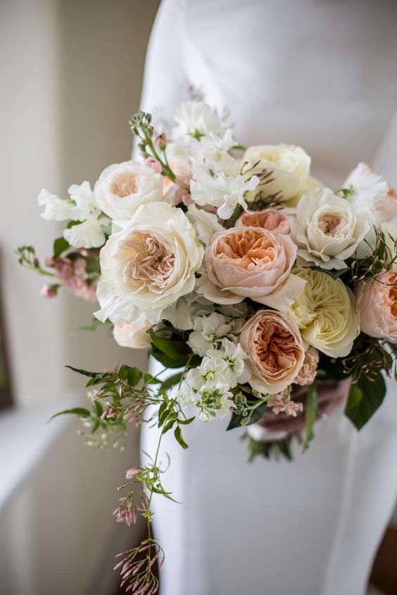 Bouquet of flowers held by a person wearing a white dress.