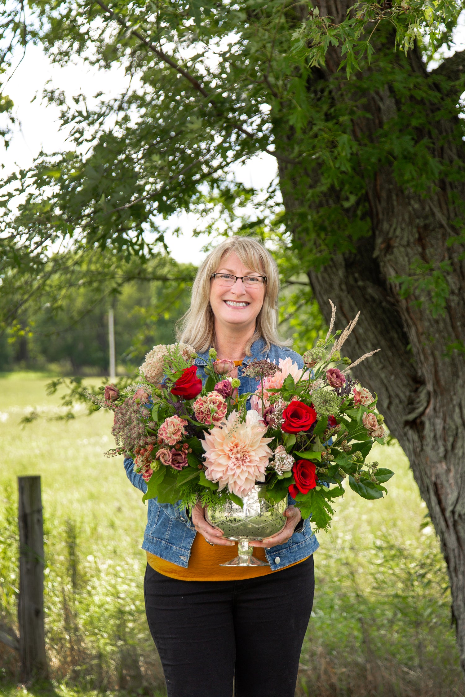 Woman holding a large bouquet of flowers outdoors near a tree